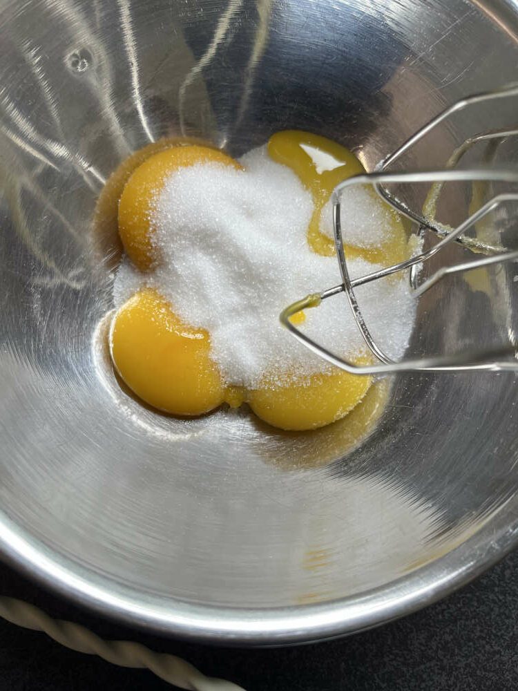 Die Eier trennen. Das Eigelb mit der Hälfte des Zuckers und dem Invertzucker in eine Schüssel tun