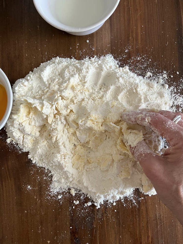 Mit den Fingerspitzen Mehl und Butter miteinander zerkrümeln, bis eine sandartige Masse entsteht