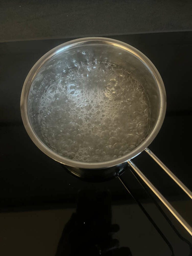Wasser, Zucker und Glucose Sirup kochend im Topf
