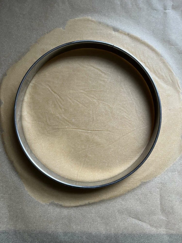 Den Teig zwischen 2 Blättern Backpapier ausrollen