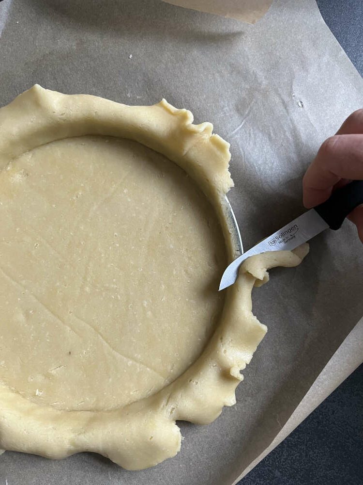 Den überstehenden Rand vom Teig abschneiden