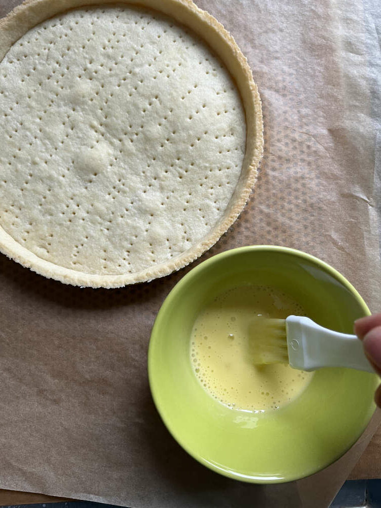 Die inneren und äußeren Ränder sowie den Boden mit der Eigelb-Sahne-Mischung bestreichen
