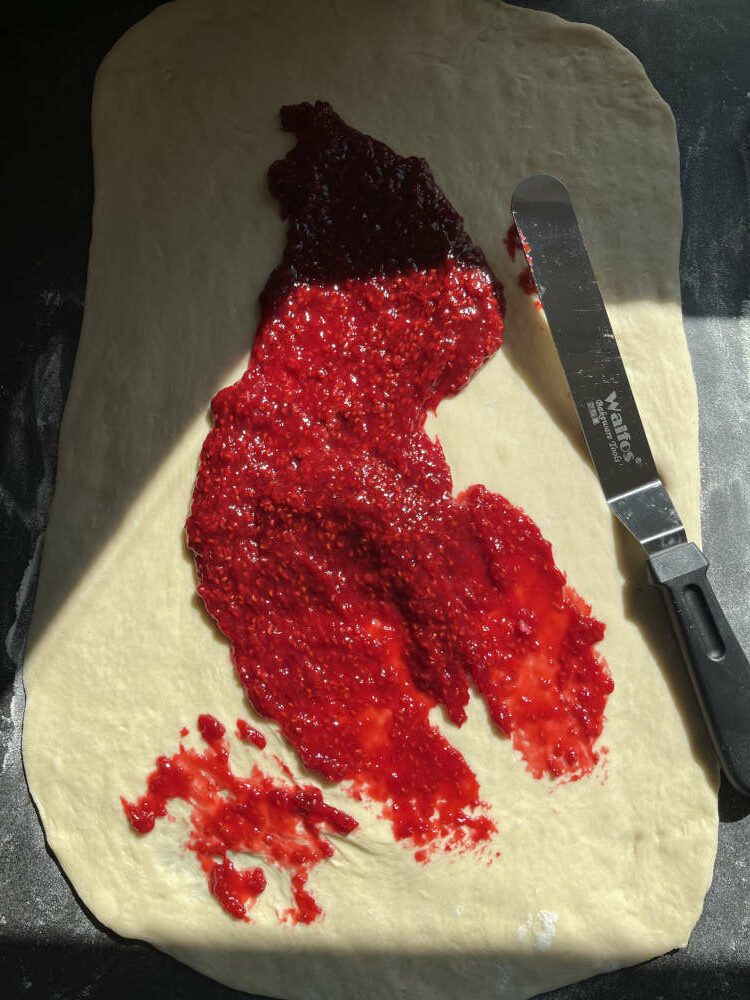 Die eingekochten Himbeeren auf dem Teig verteilen
