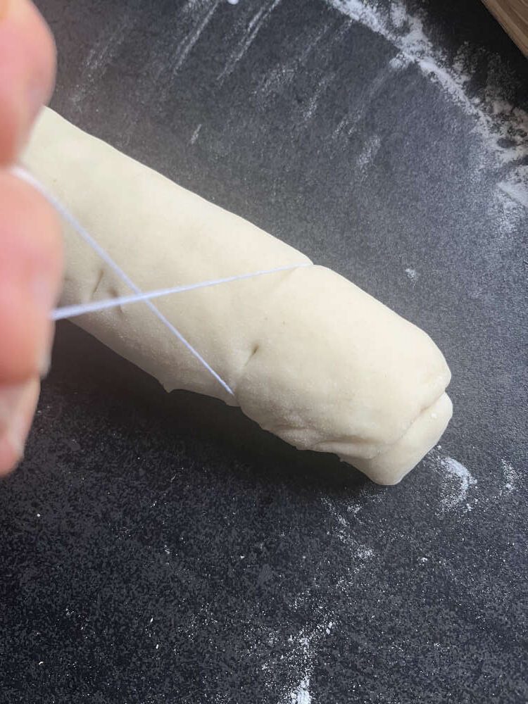 Einen Faden unter die Rolle legen, dann oben überkreuzen und zusammenziehen