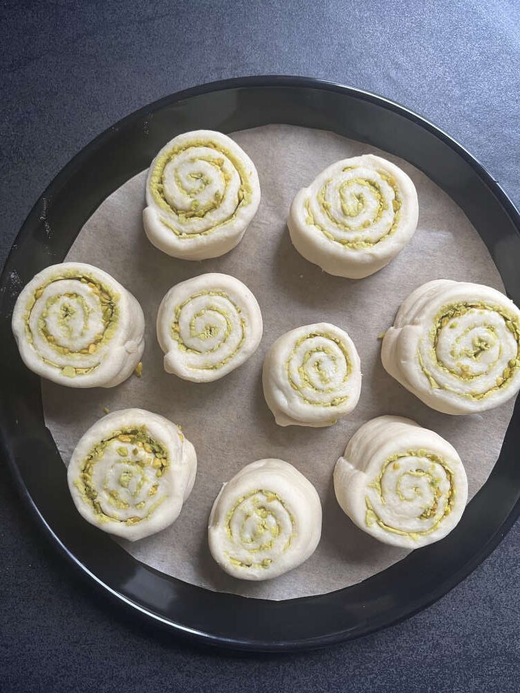 Die Teigschnecken in eine runde, mit Backpapier ausgelegte Backform legen