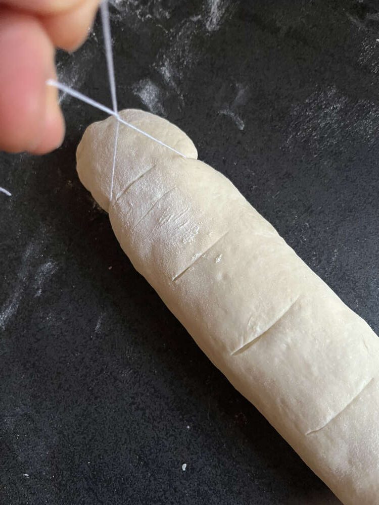 Mit einem Faden von der Teigrolle Schnecken abschneiden