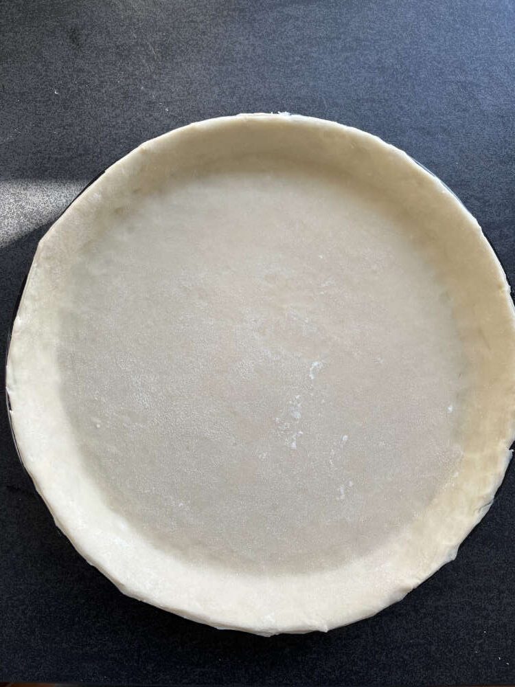 Eine Tarteform mit dem Blätterteig auskleiden