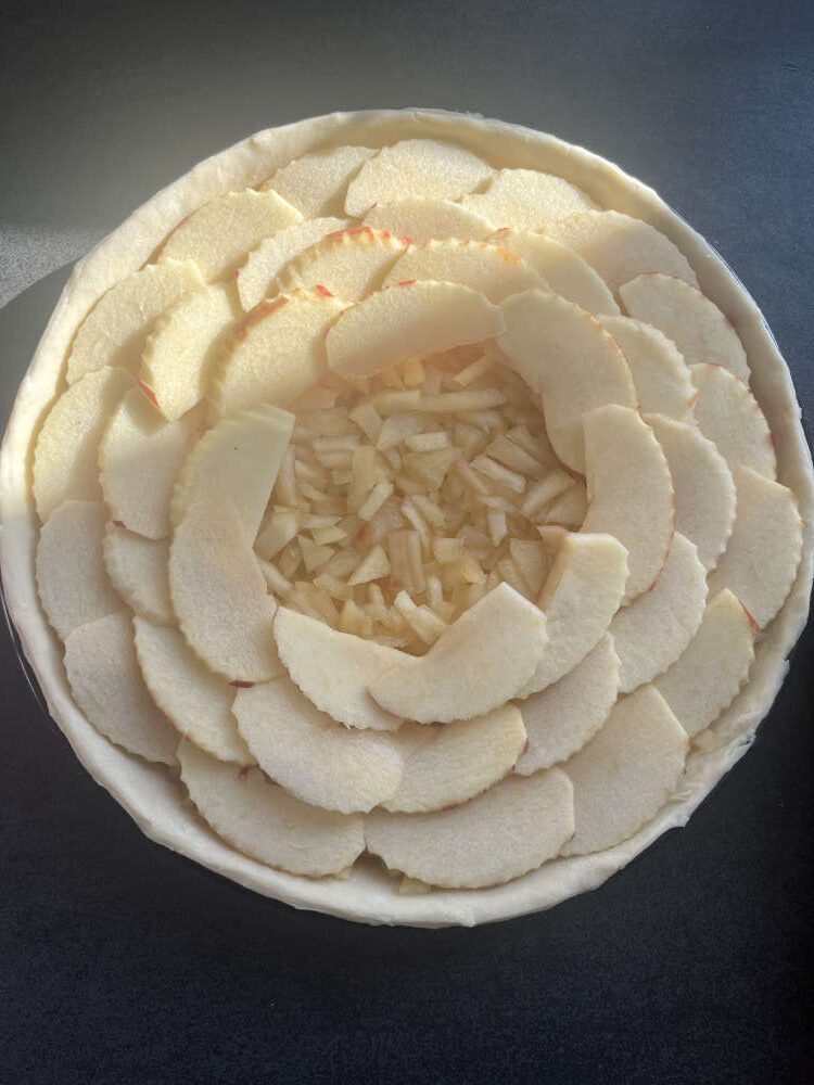 Die Apfelscheiben dachziegelartig auf der Tarte verteilen