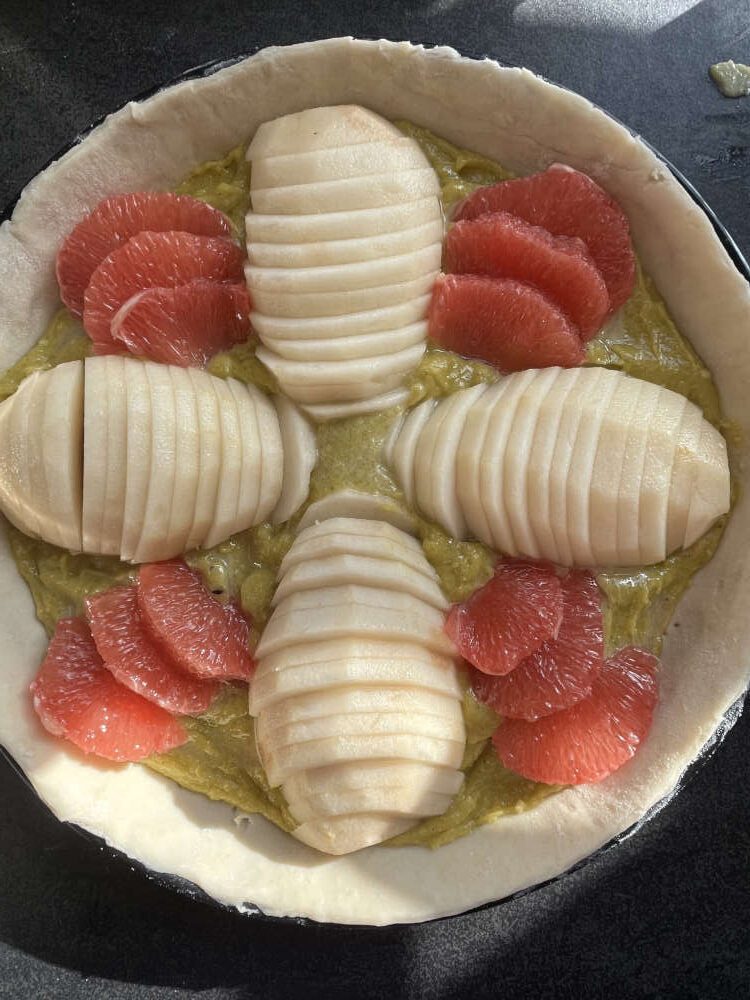 Die Birnenscheiben und die Grapefruitstücke auf der Tarte anrichten
