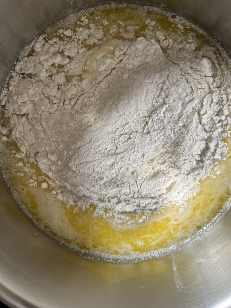 Das Mehl in einem Mal hinzufügen und mit einem Holzlöffel alles glatt verrühren, wobei der Topf auf der heißen Herdplatte stehen bleibt