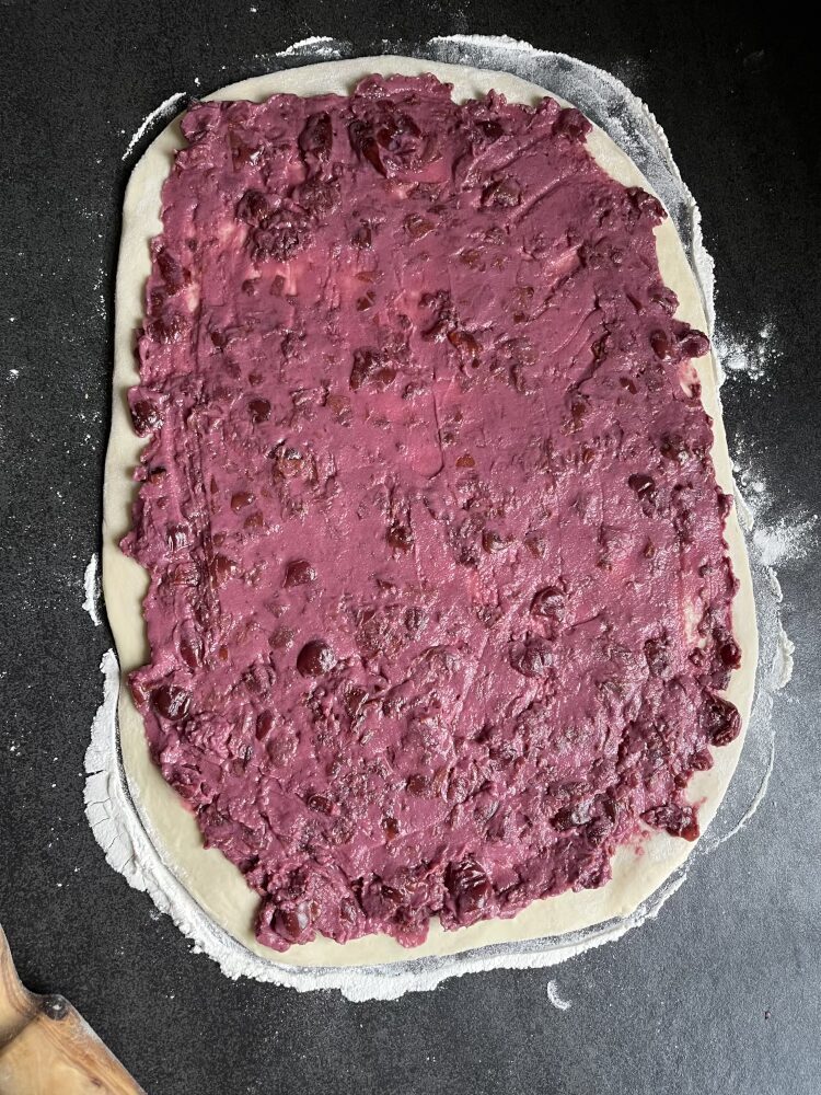 Die Kirsch-Marzipan-Füllung auf dem Teig verstreichen
