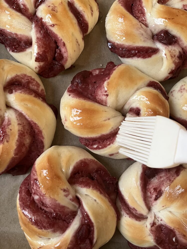 Die lauwarmen Hefeschnecken mit dem Sirup bestreichen